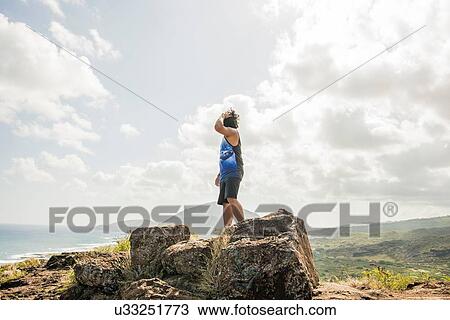 Stock Image - Young man looking out from Makapuu coast path, Oahu, Hawaii, USA. Fotosearch