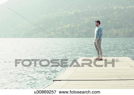 Young man looking out from pier, Lake Mergozzo, Verbania, Piemonte, Italy View Large Photo Image Stock Photo - Young man looking out from pier, Lake Mergozzo, Verbania, Piemonte, Italy. Fotosearch