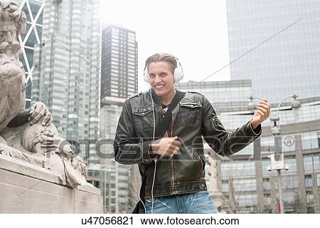 Stock Image - Young man on street playing air guitar, New York, USA. Fotosearch