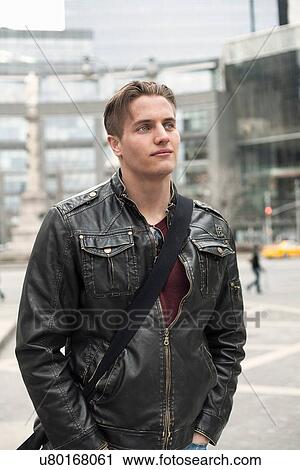 Stock Image - Young man with hands in pockets strolling on street, New York, USA. Fotosearch