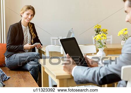 Stock Image - Young woman and man in cafe using laptop and digital tablet. Fotosearch