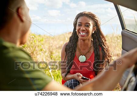 Young woman at open car door holding smartphone smiling View Large Photo Image Stock Photo - Young woman at open car door holding smartphone smiling. Fotosearch