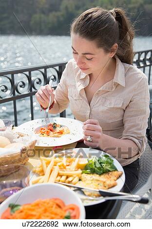 Young woman eating lunch at lakeside restaurant, Lake Mergozzo, Verbania, Piemonte, Italy View Large Photo Image Stock Image - Young woman eating lunch at lakeside restaurant, Lake Mergozzo, Verbania, Piemonte, Italy. Fotosearch
