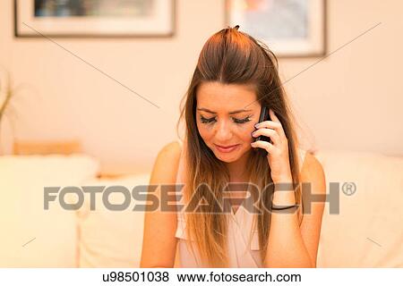 Stock Photo - Young woman having telephone conversation, crying. Fotosearch