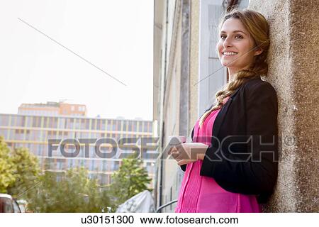 Young woman leaning against cafe wall drinking espresso View Large Photo Image Stock Image - Young woman leaning against cafe wall drinking espresso. Fotosearch