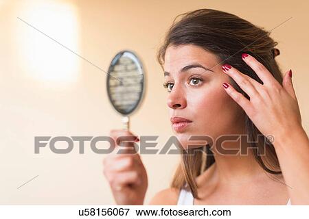 Young woman looking in hand mirror View Large Photo Image Stock Photo - Young woman looking in hand mirror. Fotosearch
