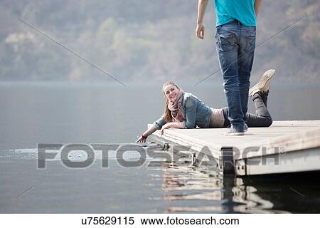 Stock Photography - Young woman lying on pier at Lake Mergozzo, Verbania, Piemonte, Italy. Fotosearch