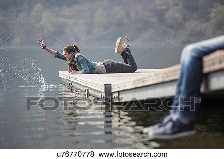 Young woman lying on pier splashing at Lake Mergozzo, Verbania, Piemonte, Italy View Large Photo Image Stock Photo - Young woman lying on pier splashing at Lake Mergozzo, Verbania, Piemonte, Italy. Fotosearch