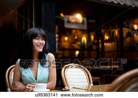 Young woman, sitting outside cafe, drinking coffee, Shanghai, China View Large Photo Image Stock Image - Young woman, sitting outside cafe, drinking coffee, Shanghai, China. Fotosearch