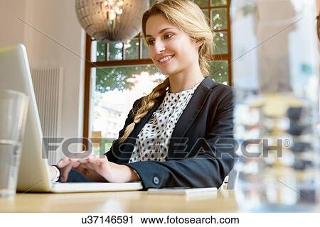 Young woman using laptop in cafe View Large Photo Image Stock Image - Young woman using laptop in cafe. Fotosearch