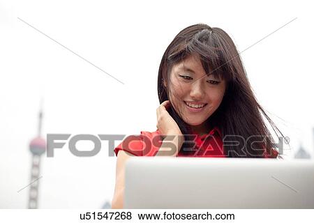 Young woman using laptop, outdoors, Shanghai, China View Large Photo Image Stock Photo - Young woman using laptop, outdoors, Shanghai, China. Fotosearch