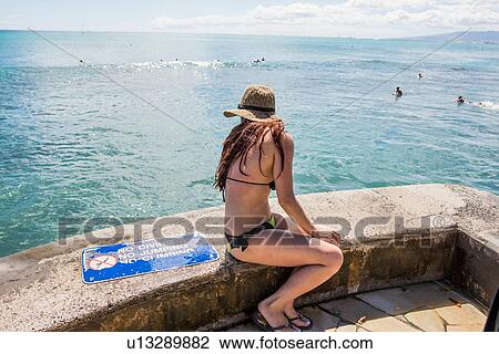 Stock Image - Young woman wearing bikini looking down on Waikiki Beach, Hawaii, USA. Fotosearch