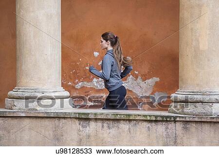 Stock Image - Young woman wearing sports clothes jogging. Fotosearch