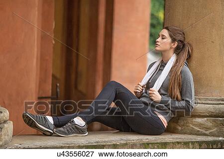 Young woman wearing sports clothes sitting resting View Large Photo Image Stock Photo - Young woman wearing sports clothes sitting resting. Fotosearch