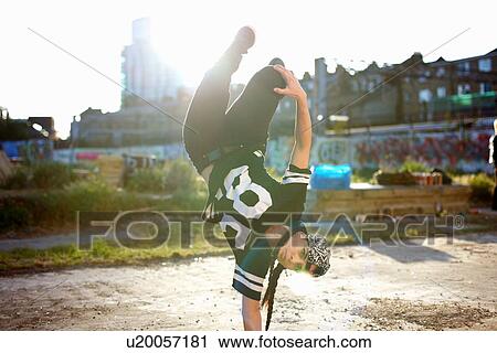 Stock Image - Young women doing upside down breakdancing freeze, looking at camera. Fotosearch