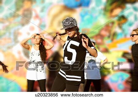 Stock Photograph - Young women holding pigtails, wearing baseball cap, looking at camera. Fotosearch