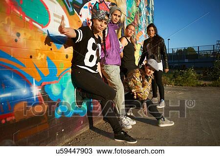 Young women leaning against graffitied wall, looking at camera View Large Photo Image Stock Image - Young women leaning against graffitied wall, looking at camera. Fotosearch