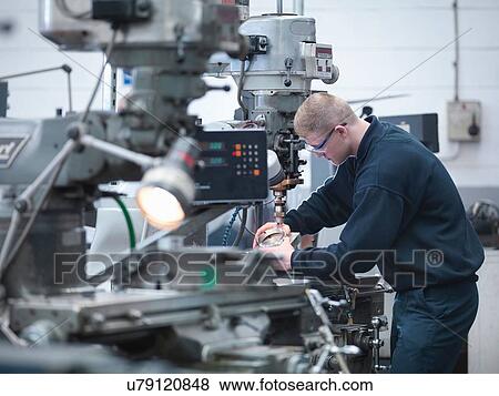 Stock Photo - Apprentice engineer on lathe in engineering factory. Fotosearch