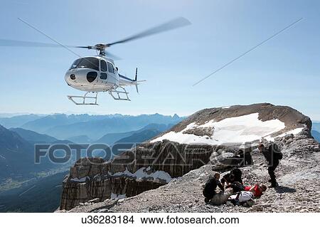 Picture - BASE jumpers preparing wingsuits on mountain summit, Dolomites, Italy. Fotosearch