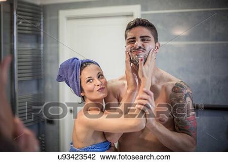Bathroom mirror image of young woman applying shaving lotion to boyfriends cheeks View Large Photo Image Stock Image - Bathroom mirror image of young woman applying shaving lotion to boyfriends cheeks. Fotosearch