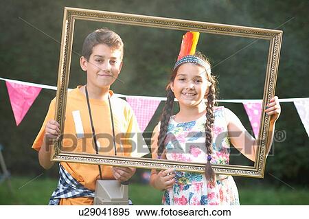 Stock Photography - Boy and girl looking through picture frame, smiling, looking at camera. Fotosearch