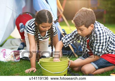 Boy and sister preparing bucket for campfire in garden View Large Photo Image Stock Photograph - Boy and sister preparing bucket for campfire in garden. Fotosearch