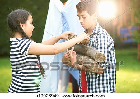 Boy and sister preparing logs for campfire in garden View Large Photo Image Stock Photo - Boy and sister preparing logs for campfire in garden. Fotosearch