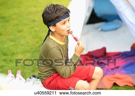 Boy eating ice lolly in front of homemade tent in garden View Large Photo Image Stock Image - Boy eating ice lolly in front of homemade tent in garden. Fotosearch