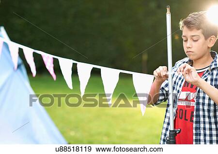 Stock Photo - Boy tying bunting to pole in garden. Fotosearch