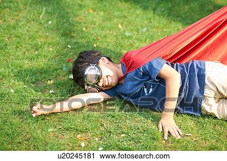 Boy wearing goggles and cape lying on side on grass, flying stance View Large Photo Image Stock Image - Boy wearing goggles and cape lying on side on grass, flying stance. Fotosearch