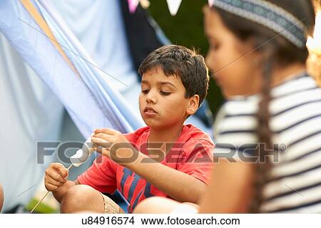 Brother and sister eating toasted marshmallows in garden View Large Photo Image Picture - Brother and sister eating toasted marshmallows in garden. Fotosearch