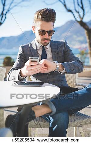 Businessman checking the time at lakeside cafe, Rovato, Brescia, Italy View Large Photo Image Picture - Businessman checking the time at lakeside cafe, Rovato, Brescia, Italy. Fotosearch