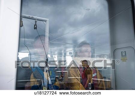 Picture - Captain and female scientist reflected in window on research ship. Fotosearch