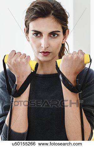 Close up of young woman exercising with resistance bands in living room View Large Photo Image Stock Photograph - Close up of young woman exercising with resistance bands in living room. Fotosearch