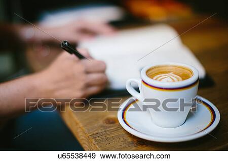 Coffee cup on table and womans hands writing in notebook View Large Photo Image Stock Photo - Coffee cup on table and womans hands writing in notebook. Fotosearch