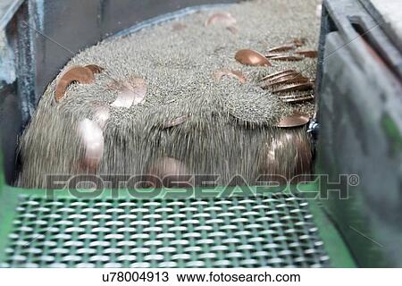 Stock Image - Copper washers being smoothed in engineering factory, close up. Fotosearch