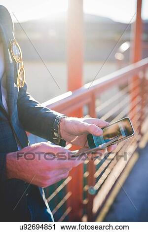 Cropped close up of young mans hands using digital tablet and smartphone on footbridge View Large Photo Image Stock Image - Cropped close up of young mans hands using digital tablet and smartphone on footbridge. Fotosearch
