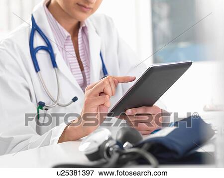 Stock Photo - Cropped shot of female doctor using digital tablet touchscreen to update medical records. Fotosearch