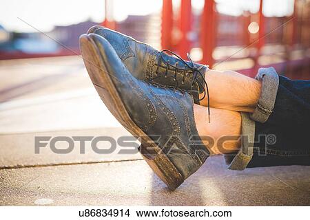 Picture - Cropped shot of young mans bare ankles and brogues on sidewalk. Fotosearch