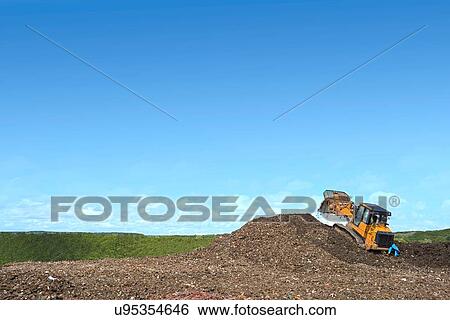 Digger on mound burying waste on landfill site View Large Photo Image Stock Photograph - Digger on mound burying waste on landfill site. Fotosearch