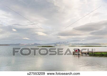 Stock Photo - Distant view of hikers unpacking on lake pier, Thingvellir, Iceland. Fotosearch