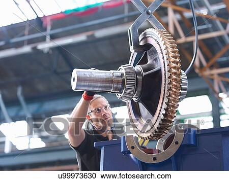 Stock Image - Engineer assembling industrial gearbox in engineering factory. Fotosearch