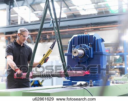 Stock Photo - Engineer assembling industrial gearbox in engineering factory. Fotosearch