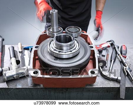 Stock Photo - Engineer assembling industrial gearbox in engineering factory, close up. Fotosearch