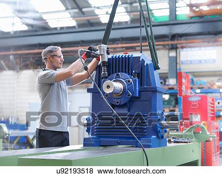 Stock Photo - Engineer assembling industrial gearbox in engineering factory. Fotosearch