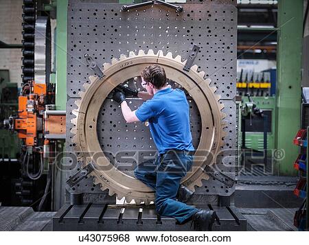 Engineer fitting gear wheel on lathe in engineering factory View Large Photo Image Stock Photo - Engineer fitting gear wheel on lathe in engineering factory. Fotosearch