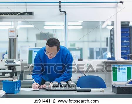 Stock Image - Engineer inspecting artificial hip joint parts in quality control department in orthopaedic factory. Fotosearch
