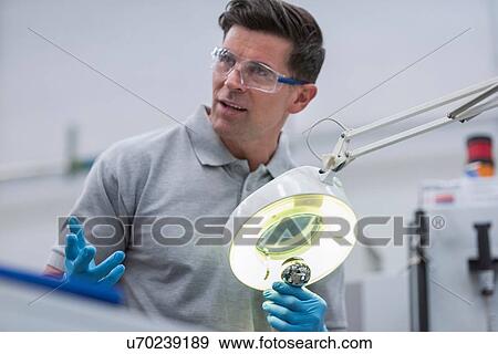 Stock Photo - Engineer inspecting artificial hip joint in orthopaedic factory. Fotosearch