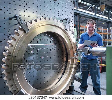 Engineer inspecting drawing on digital tablet of gear wheel on lathe in engineering factory View Large Photo Image Stock Photo - Engineer inspecting drawing on digital tablet of gear wheel on lathe in engineering factory. Fotosearch