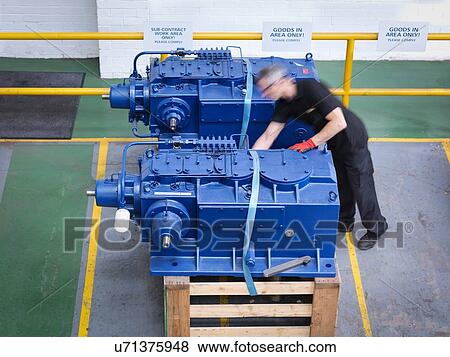 Stock Photo - Engineer preparing gearboxes for shipping in engineering factory. Fotosearch